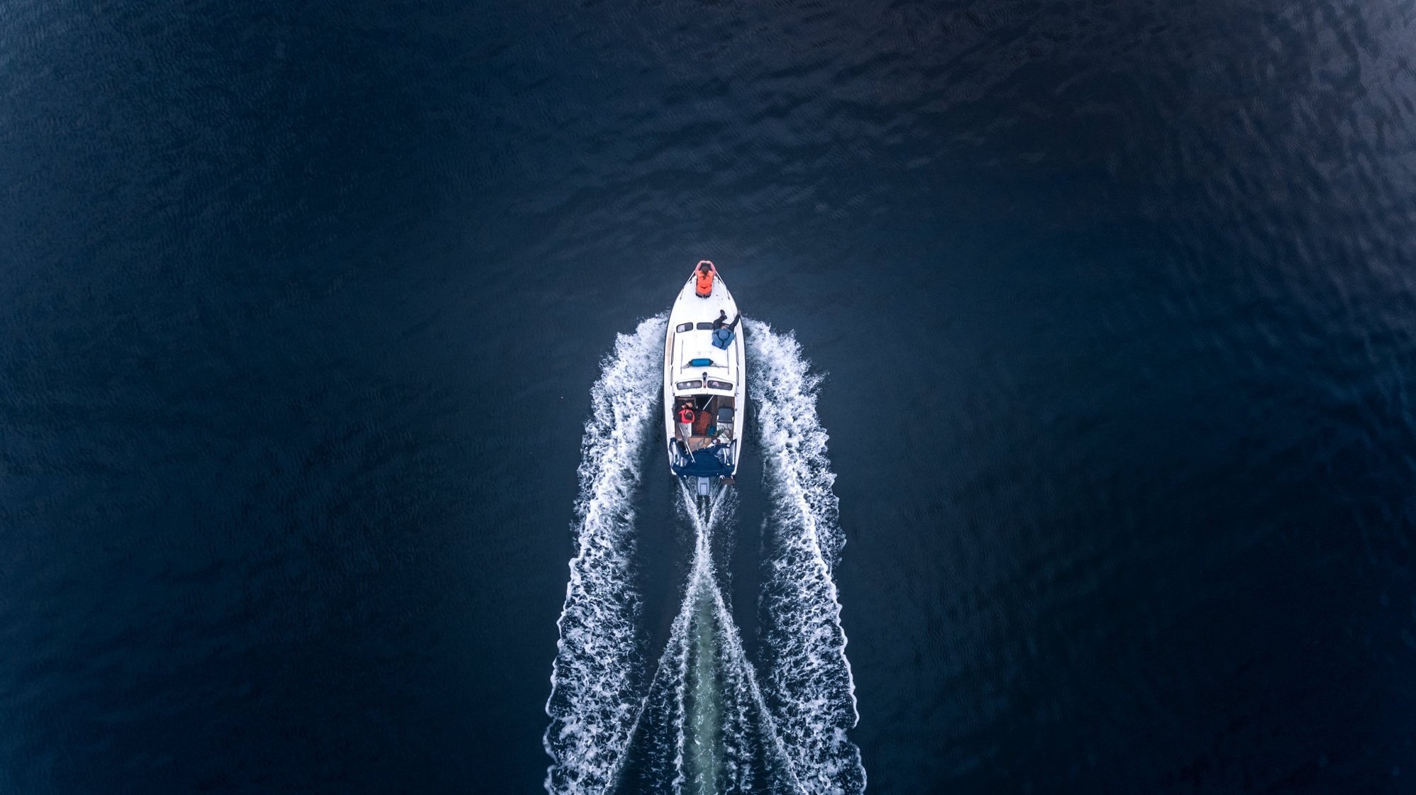 Family on small boat cruising in the evening - top view from a drone